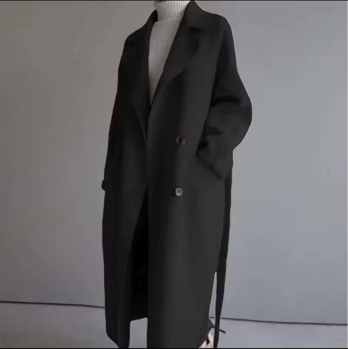 Black coat on a mannequin against a plain background